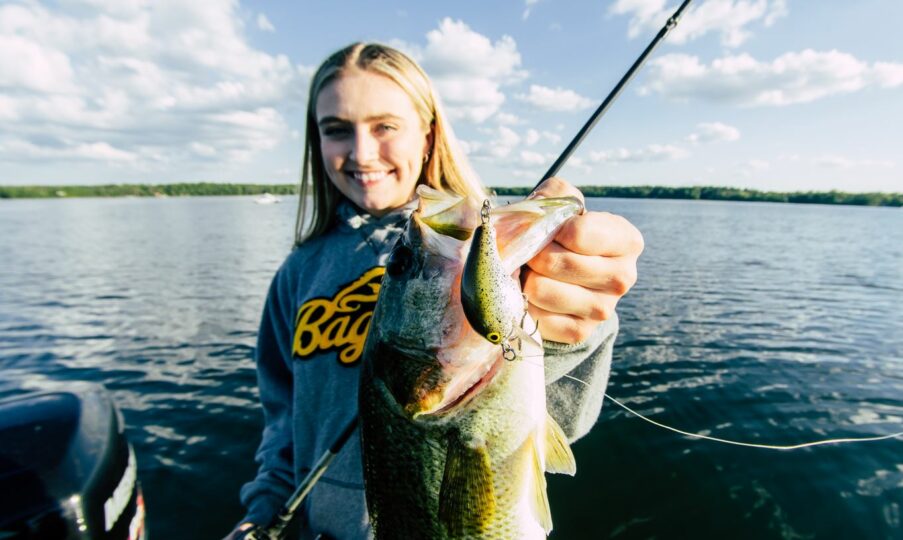 Female fisherman holding up a largemouth bass caught on a new colored Bagley Bait balsa crankbait.
