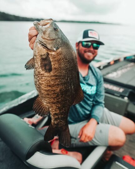 Drew Benton holding up a smallmouth bass he caught on a Bagley Bait Company crankbait