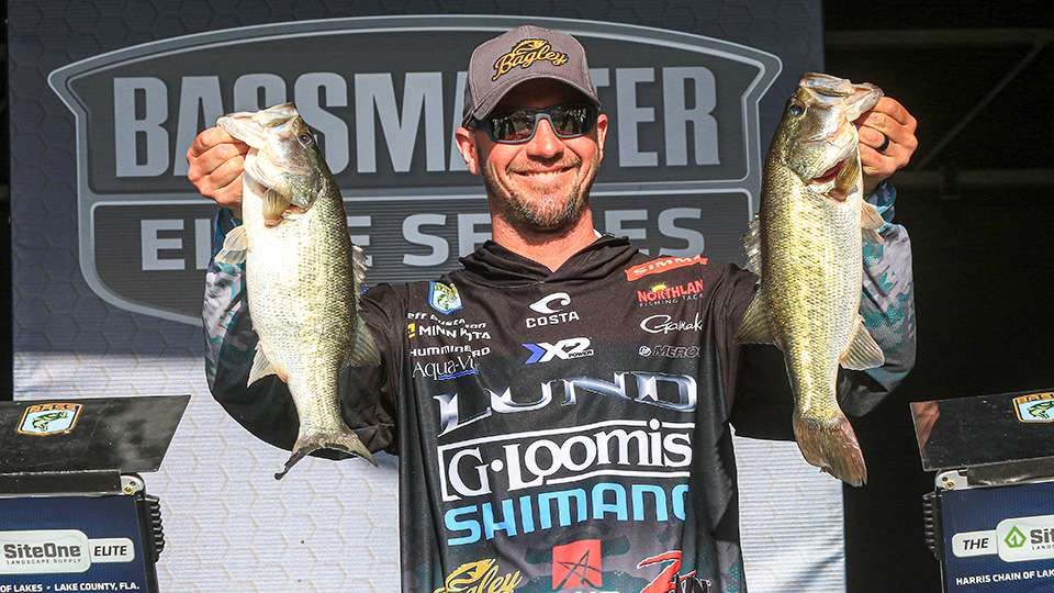 Jeff 'Gussy' Gustafson holding up two largemouth bass on the BASS Elite Series tournament stage